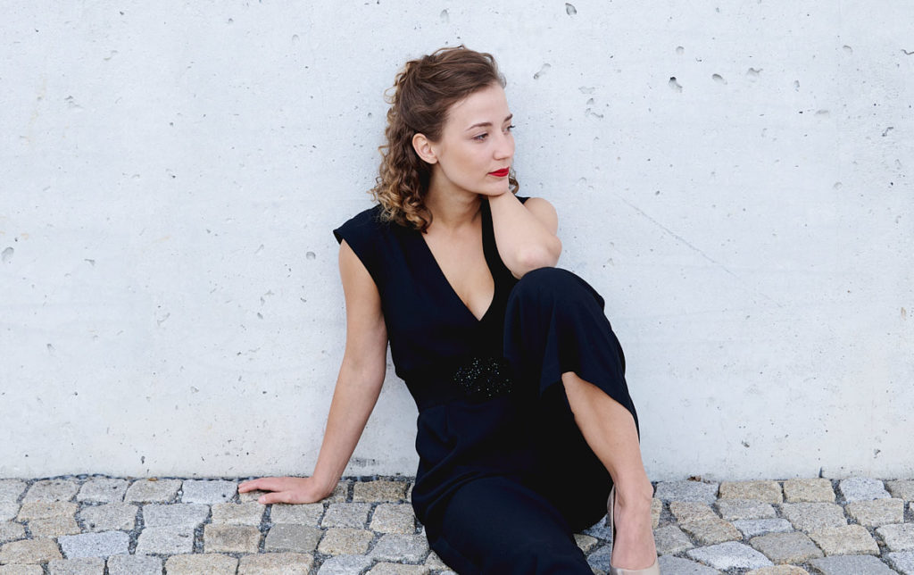 Schöne Frau sitzt auf Boden vor Haus